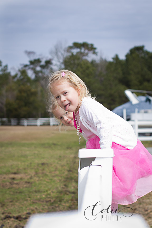 twin girls on horse pasture fence
